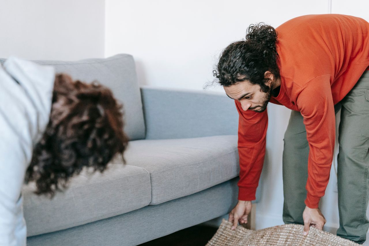 why-choose-us A pair of people straightening up their living room, arranging the furniture and rugs together as a team.